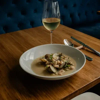 Plato de almejas y vino blanco en restaurante. alubias con almejas y una copa de vino blanco.